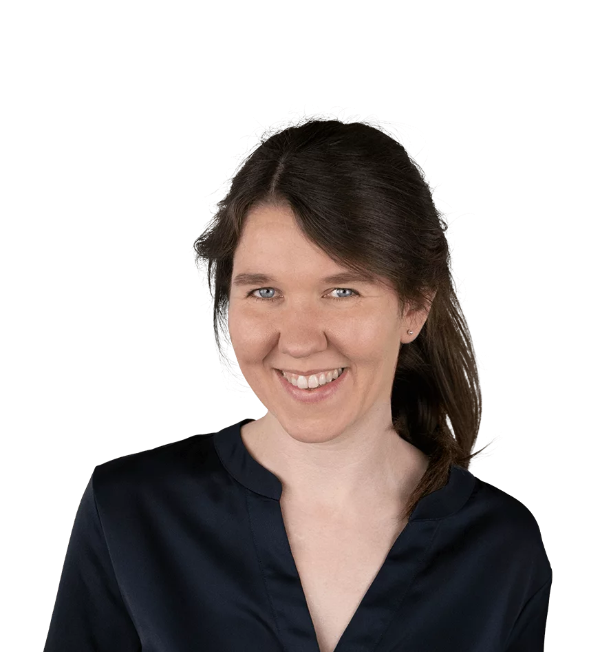 Jana Axmann - Expertin für Assessment Center und Personalentwicklung bei PE Solution. Porträt einer jungen Frau mit langen, dunkelbraunen Haaren, die zu einem seitlichen Pferdeschwanz gebunden sind. Sie trägt ein dunkelblaues Oberteil und lächelt freundlich. Der Hintergrund ist neutral mit einem transparenten Muster.