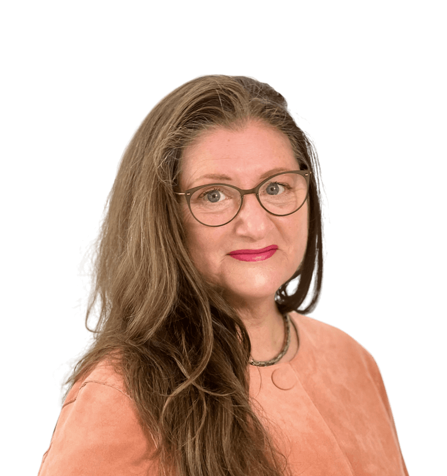 Eine Frau mit langen, braunen Haaren lächelt direkt in die Kamera. Sie trägt eine runde Brille und einen roten Lippenstift. Ihr Outfit besteht aus einem rosa Oberteil und einer Halskette. Ihr Gesichtsausdruck ist freundlich und offen. Der Hintergrund ist weiß, wodurch der Fokus vollständig auf der Frau liegt.